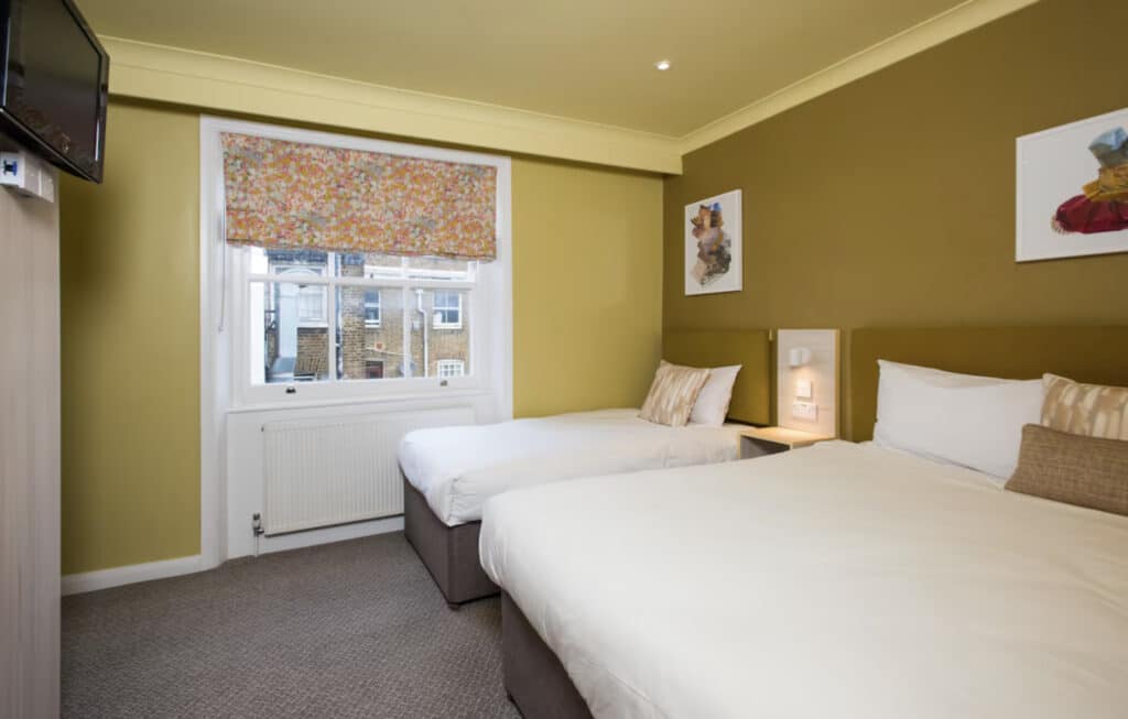 Hotellrom  med senger, vindu og gule vegger.
