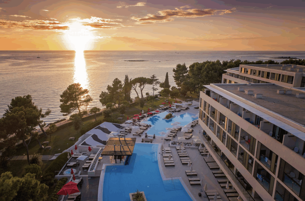 Hotell ved vannkanten, bassengområde og solnedgang.