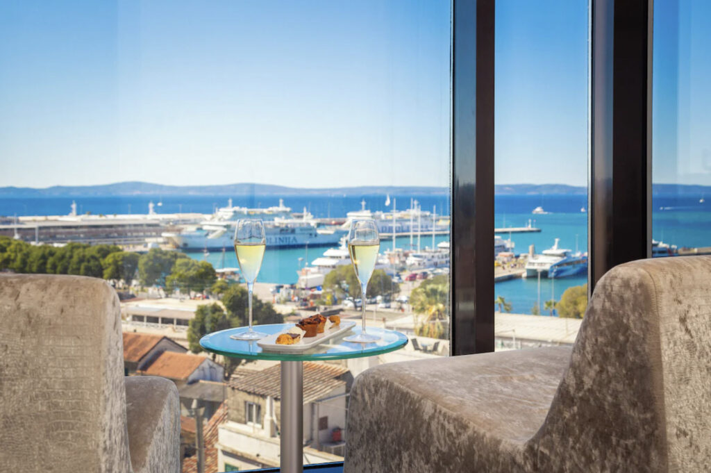 Hotellrom med utsikt over vannet. To champagneglass og to stoler.