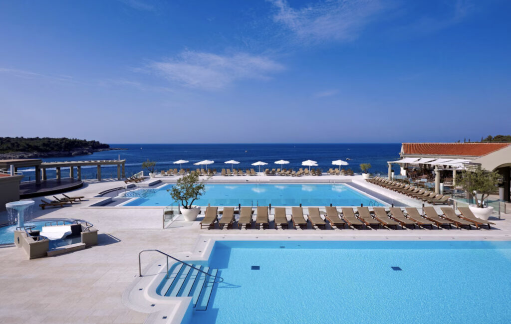 Park Plaza Verudela Pula Hotell med basseng, parasoller og utsikt over stranden.