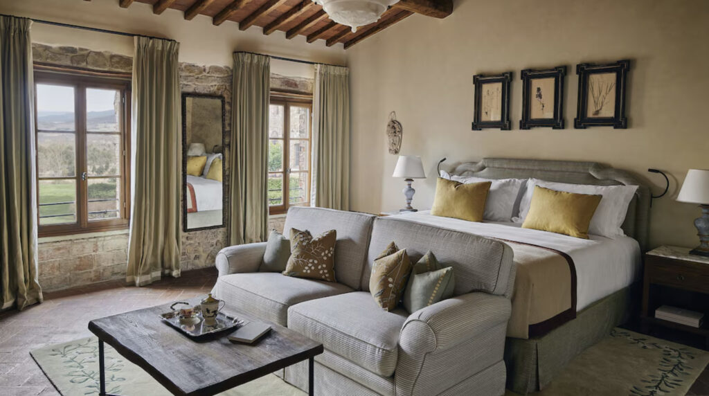 Hotellrom med dobbeltseng. sofa og store vinduer mot landet.