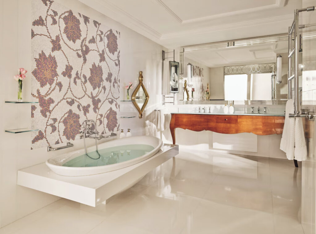 Hotellrombad med badekar, stort speil og hvite fliser.