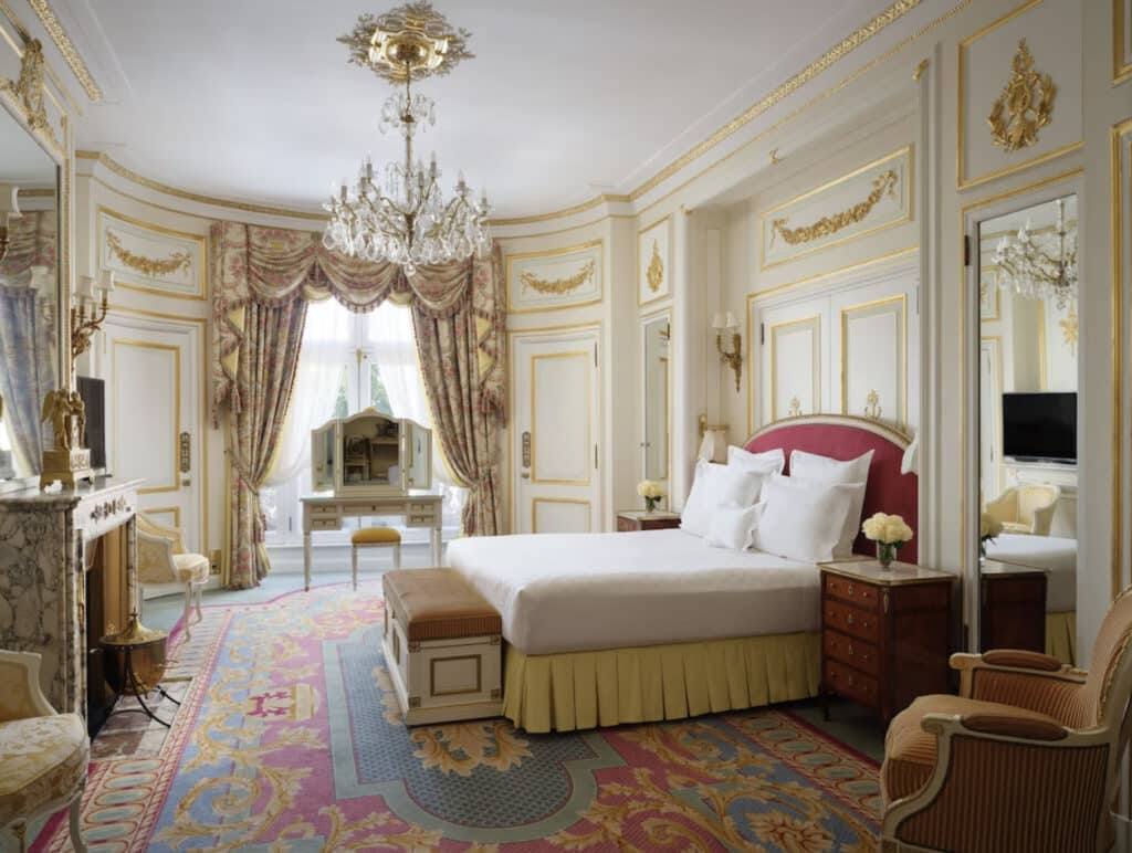 Dobbeltrom med gulldetaljer i veggene, lysekrone og et fargerikt teppe. Egen peis og sminkebord. 