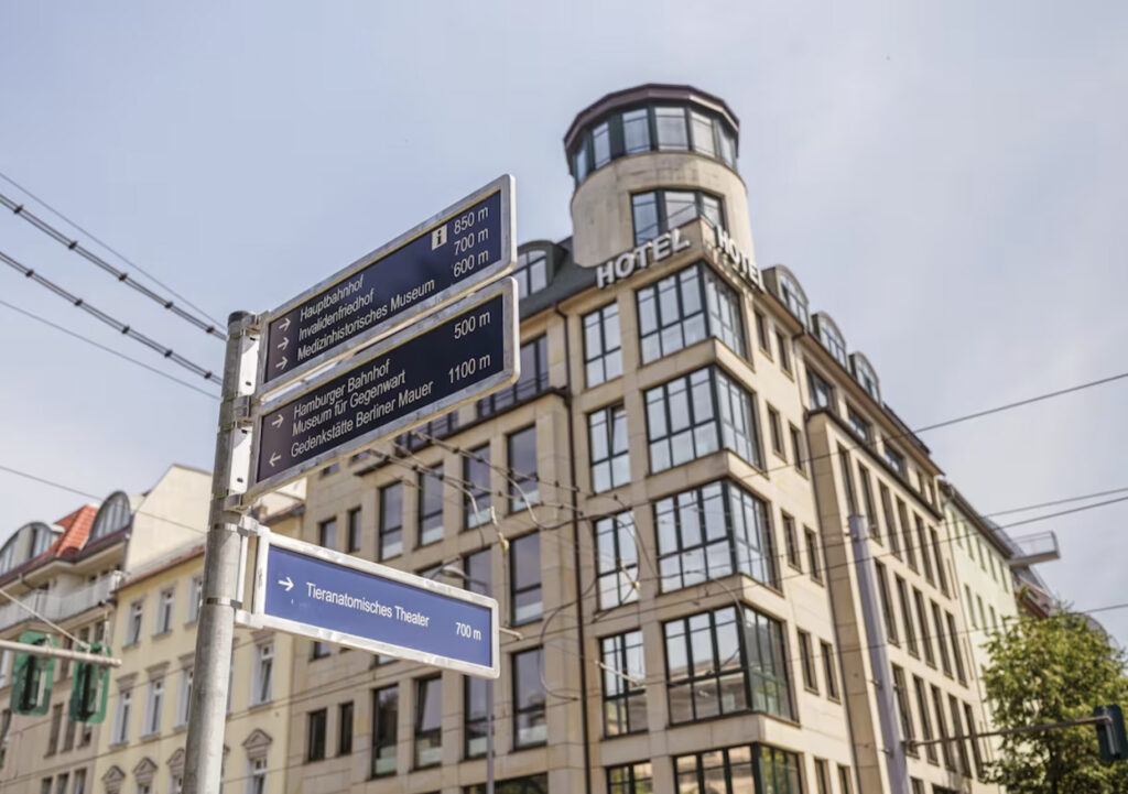 Hotellfasade med skilt til ulike steder i Berlin.