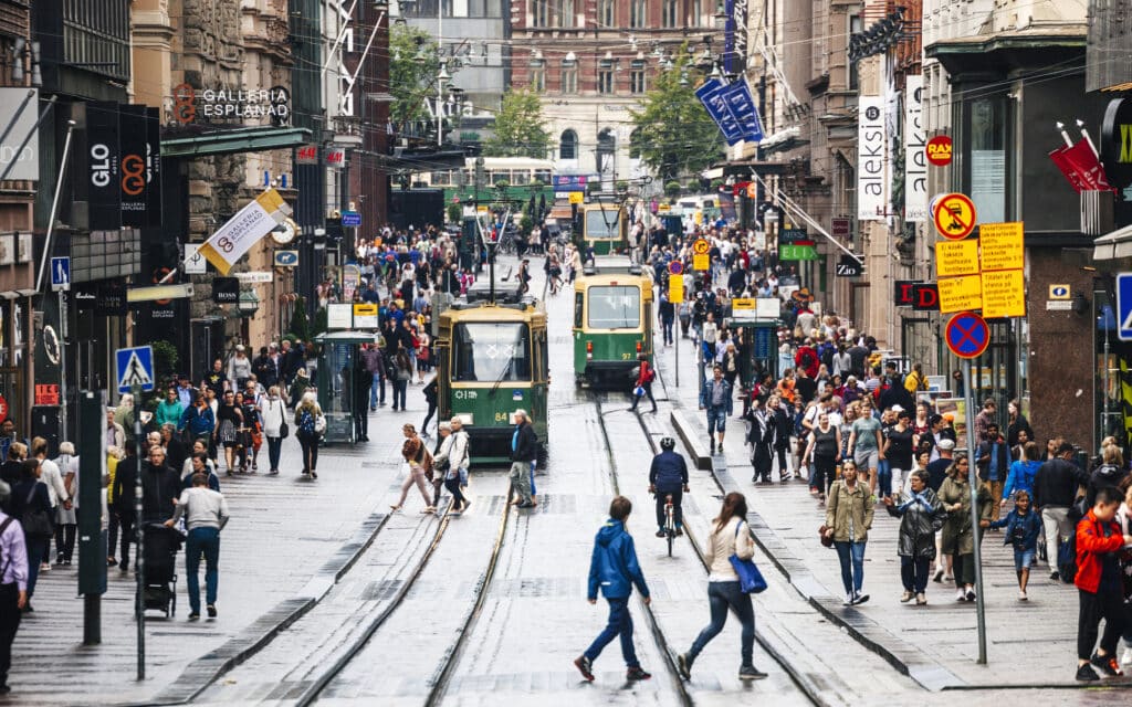 Folkemengde i Helsinkis gater med trikk og shopping.