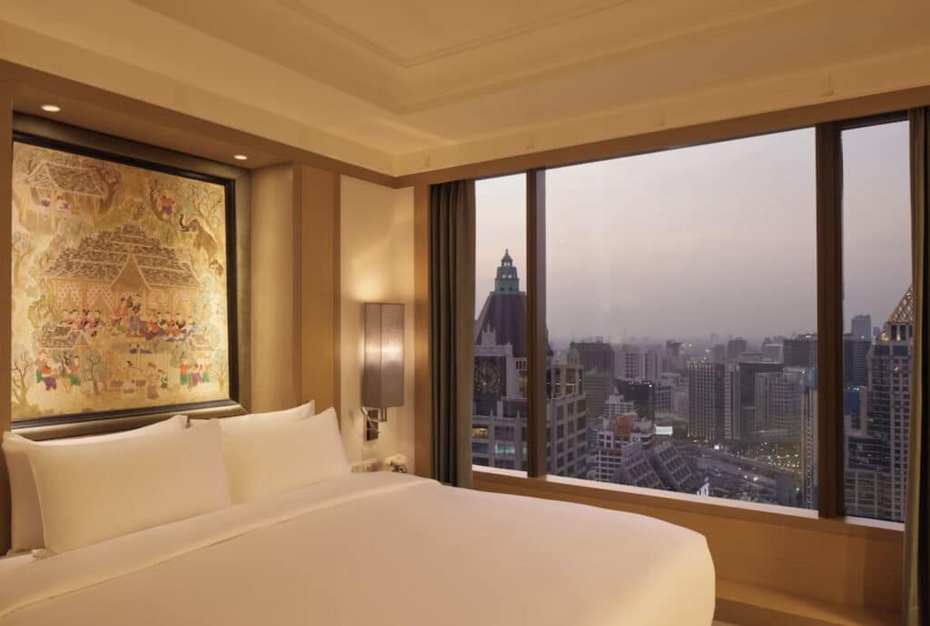 Hotelrom med dobbeltseng, stort vindu mot byen.