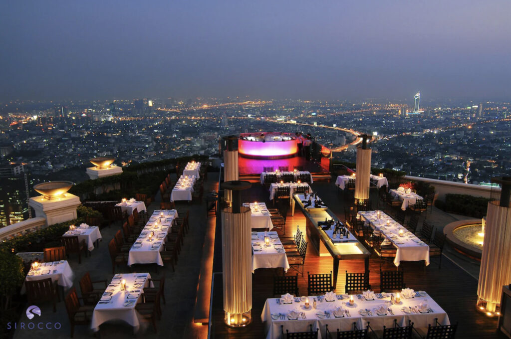 Takterrasse med bordservering og bar som lyser opp i neonlys. 