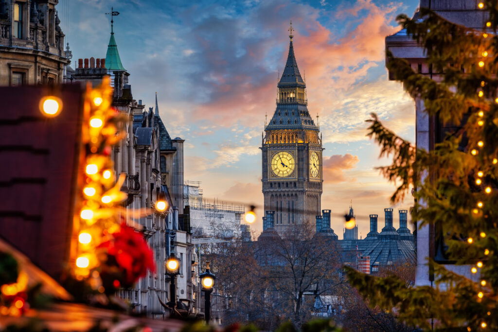 Vakker solnedgang over Big Ben i London, med lyslenene fra julemarkedet på Trafalgar Square i forgrunnen. 