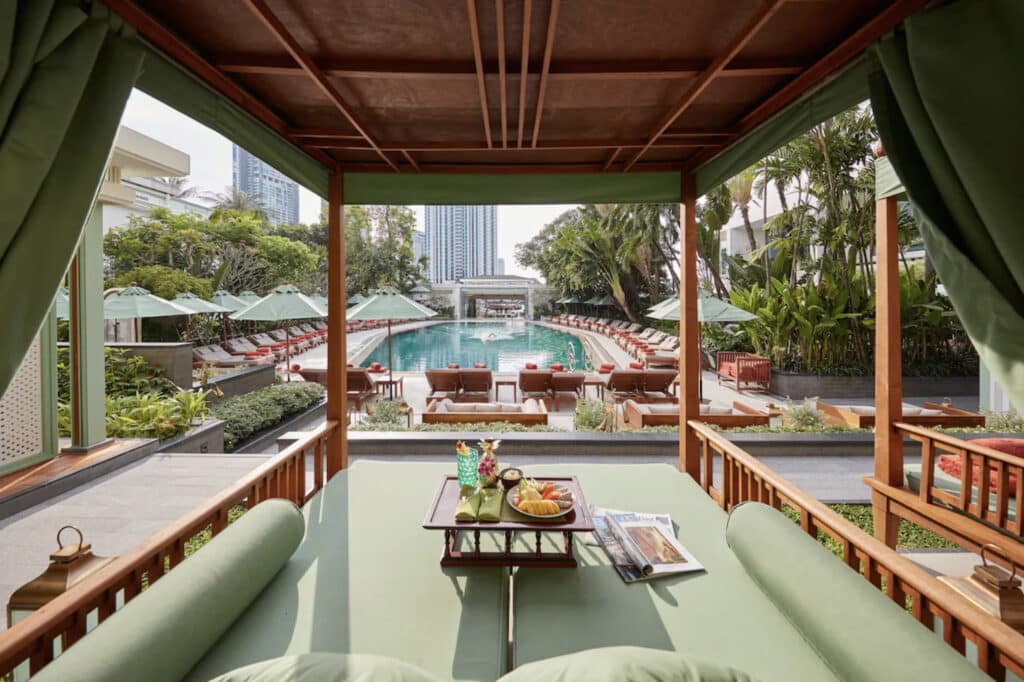 Stor solseng med servering av frukt, og stort bassengområde utendørs. 