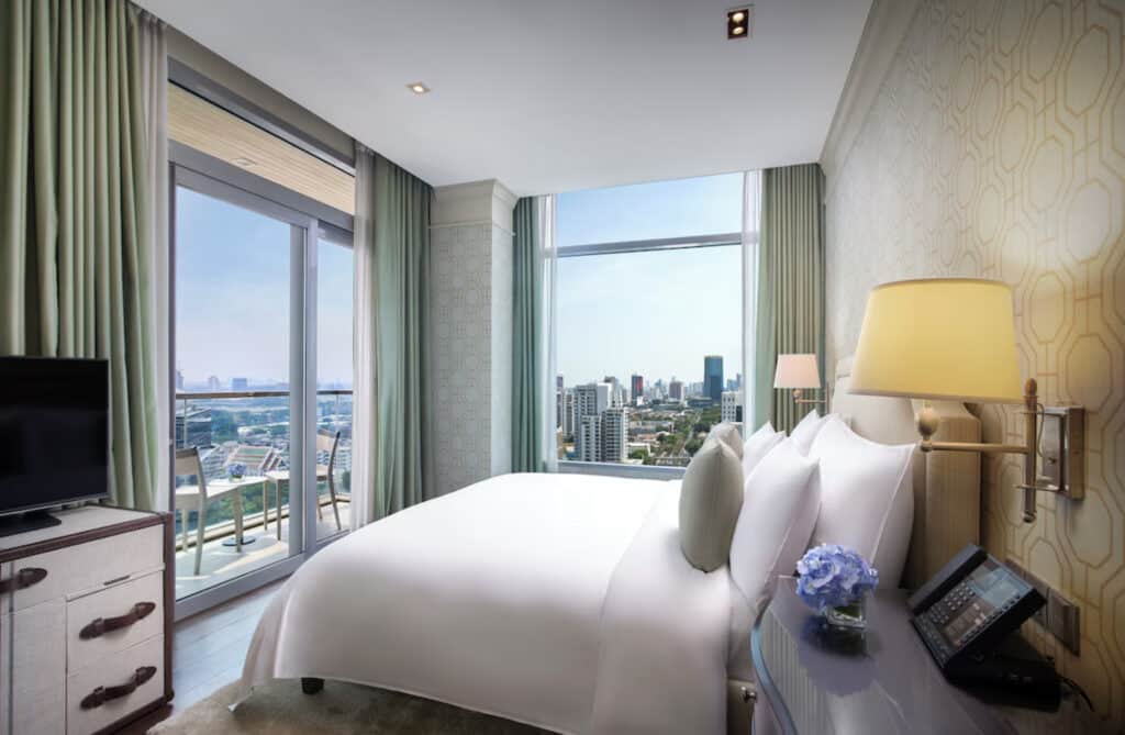 Hotellrom med store vinduer og utsikt over byen.