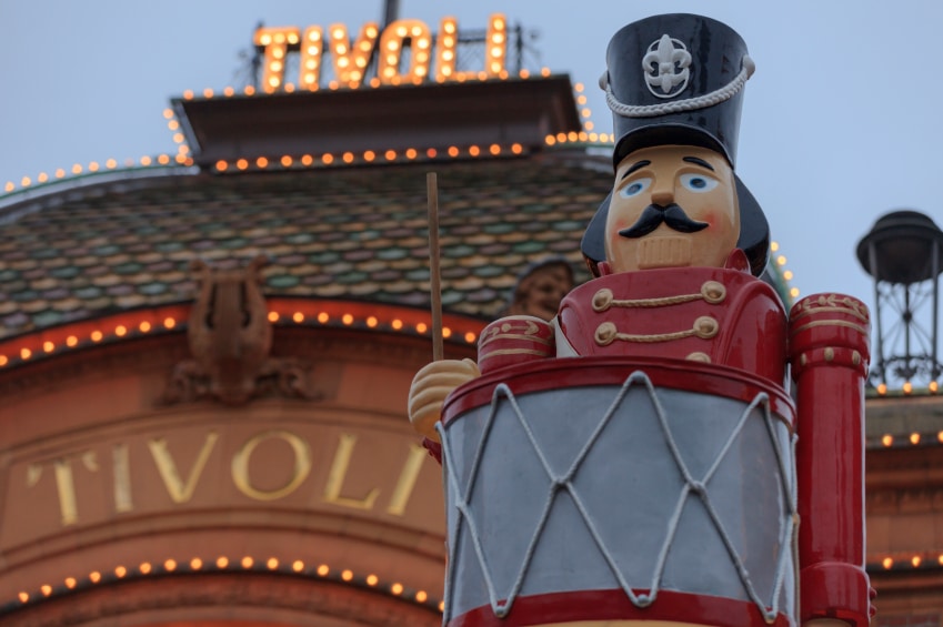 Inngangen til Tivoli med en nøtteknekker-statue foran.  Glitrende skilt.