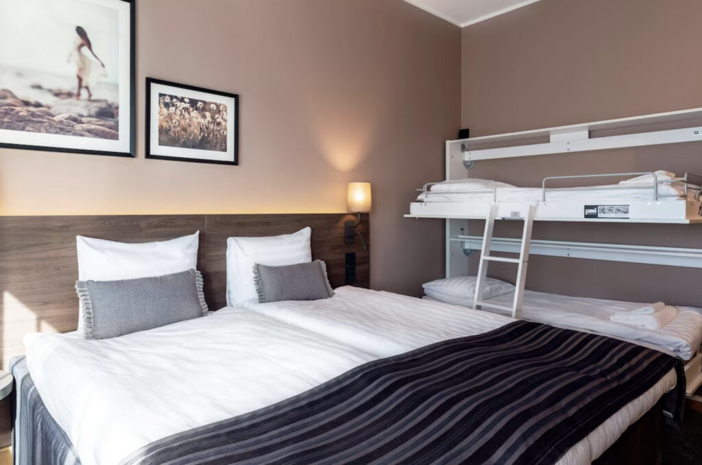 Hotellrom med dobbeltseng og køyeseng.