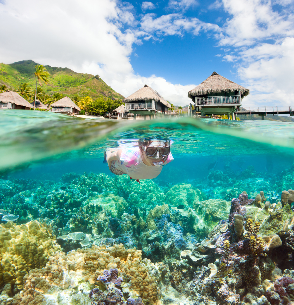 Woman snorkeling in clear tropical waters in front of overwater bungalows. Made of two photos
