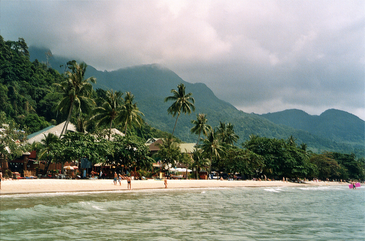 Tourists enjoying at White sand beach, surrounded by palm trees in Koh Chang's west coast, Thailand