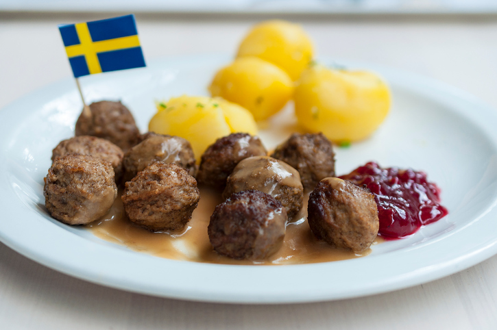 Meatballs with boiled potatoes and sweet red sauce decorated by Swedish flag - traditional Swedish dish