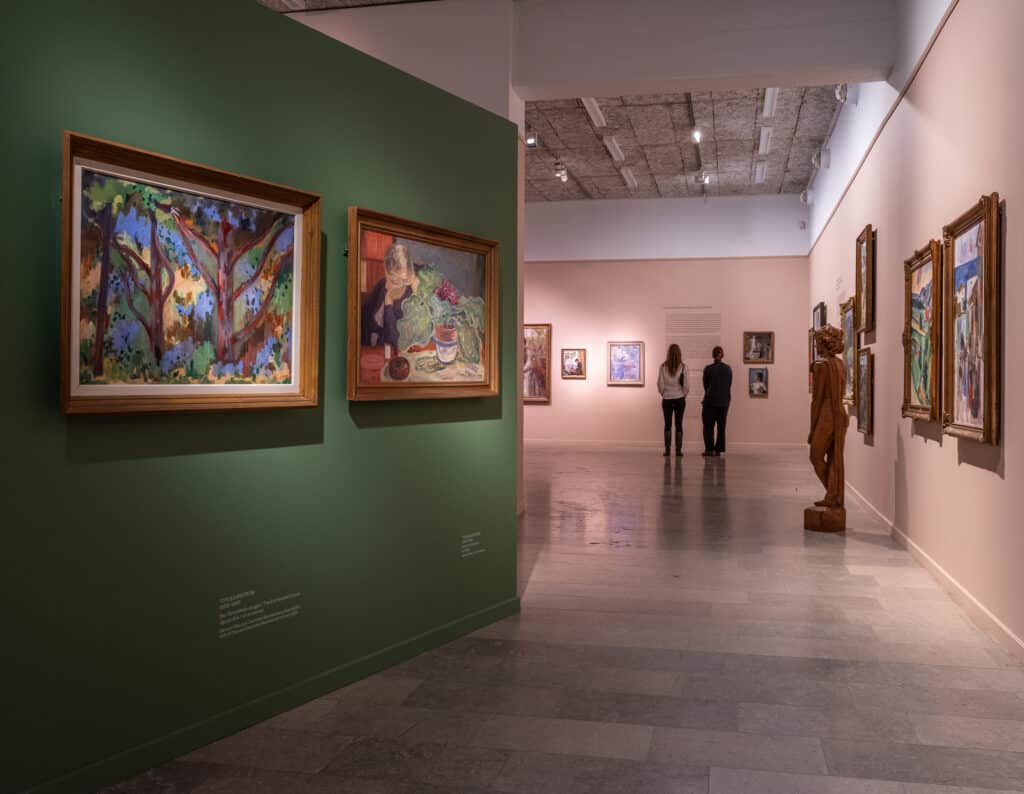 Folk som går rundt i museet og ser på kunsten. Grønn og rosa vegg.