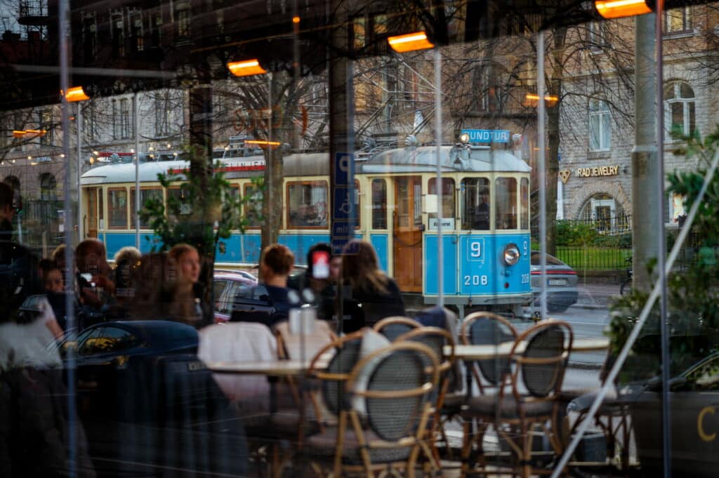 Blå trikk i Gøteborg med kafe og folk som sitter og snakker.
