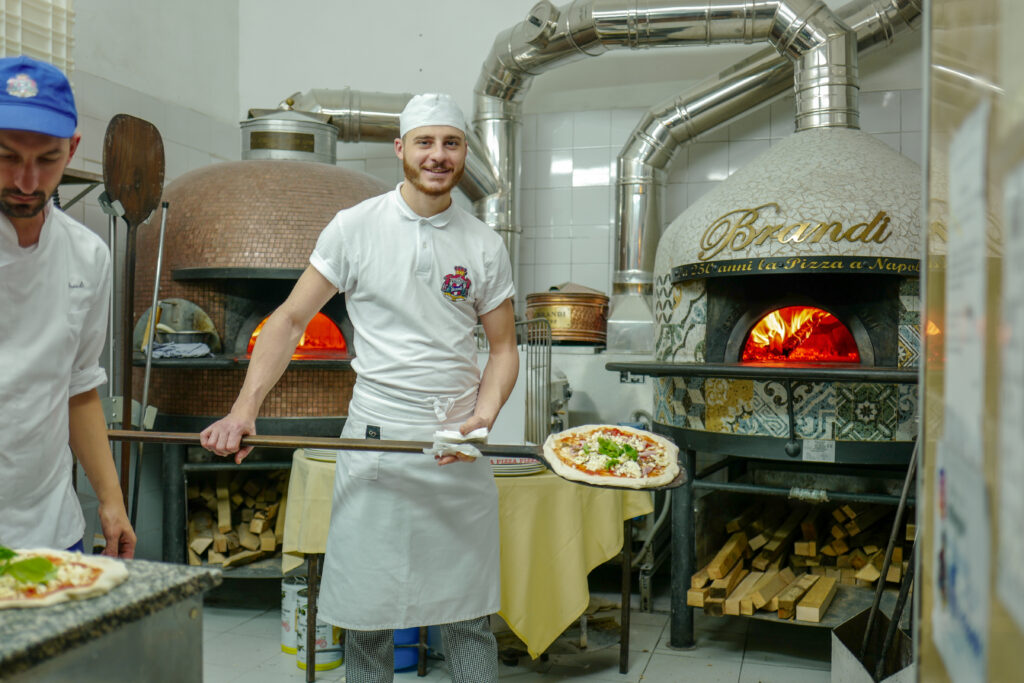 Det lages italiensk pizza i Napoli by. Bli med på ferie i Napolibukta.