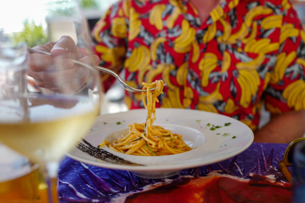 Erik Valebrokk spiser italiensk pasta i Napolibukta på restaurant. Med et glasshvitvin i bakgrunnen. Bli med på ferie i Napolibukta.