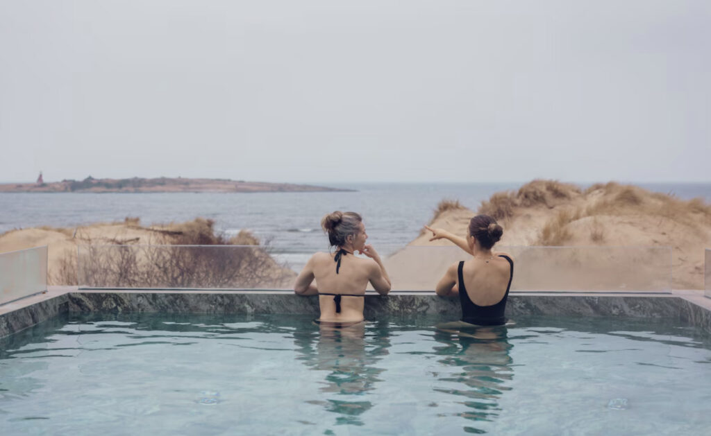 Hotel Tylosand i Halmstad. To kvinner som nyter utsikten fra hotellets utendørsbasseng. Utsikt over strand. 