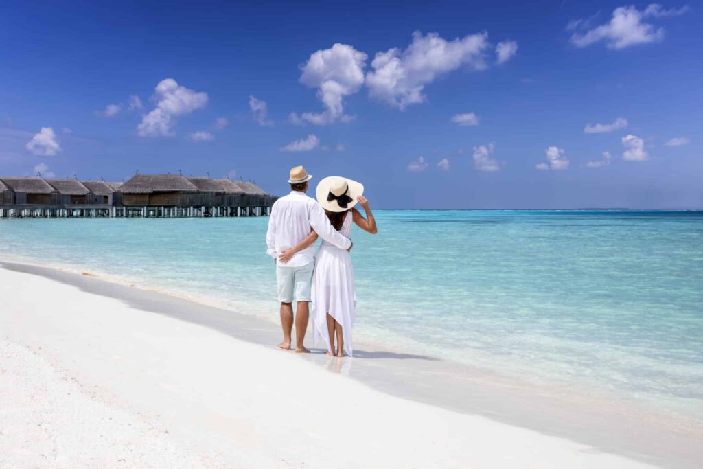 Maldivene med turkist vann, par som ser ut mot vannet og bungalows.