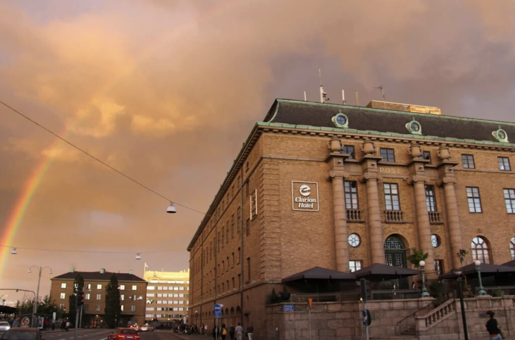 Hotellfasade med regnbue i bakgrunnen.