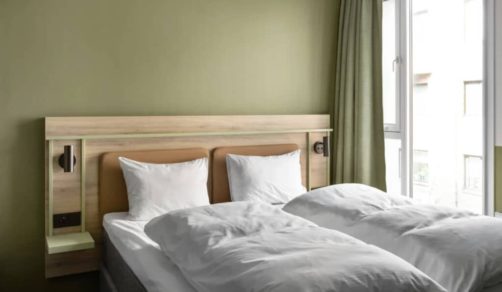 Hotellseng med hvite dyner og grønne vegger. Comfort Hotel i Trondheim, Norge. Hotell Strawberry.