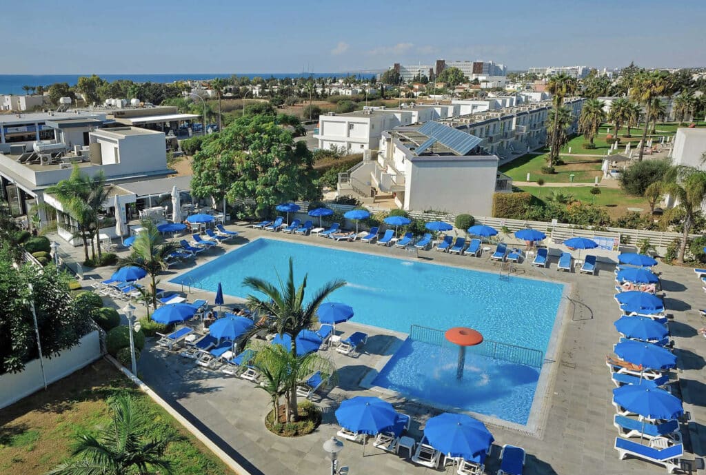 EuroNapa i Ayia Napa. Utendørs basseng med parasoller og grønne trær.