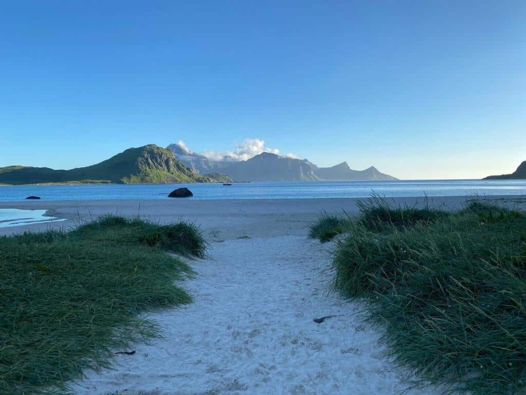 Strand, sand og grønt gress.