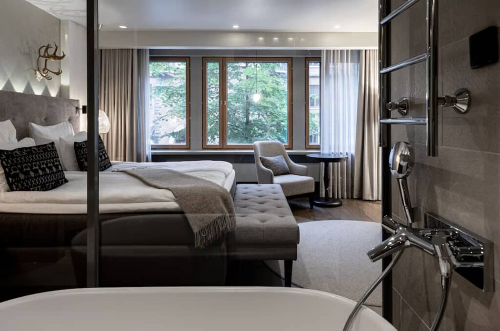 Hotellrom med finske mønstre på puter, og elgehode på veggen. Badekar i rommet og stor dobbeltseng. Hva med en reise til Finland?