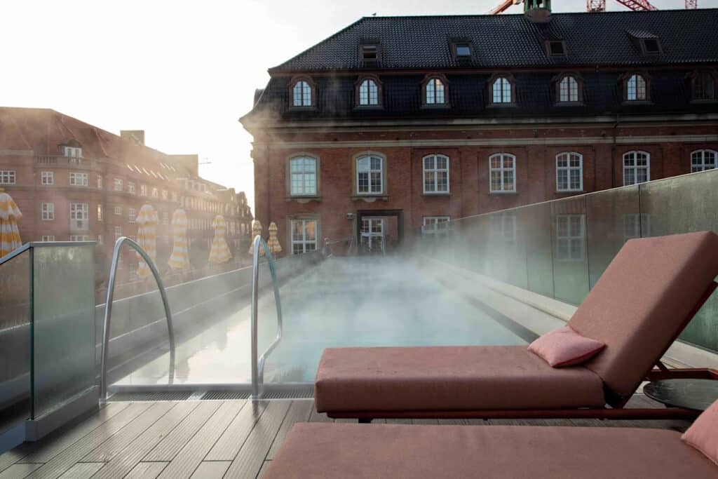 Villa Copenhagen med takbasseng, to solsenger og bygninger.