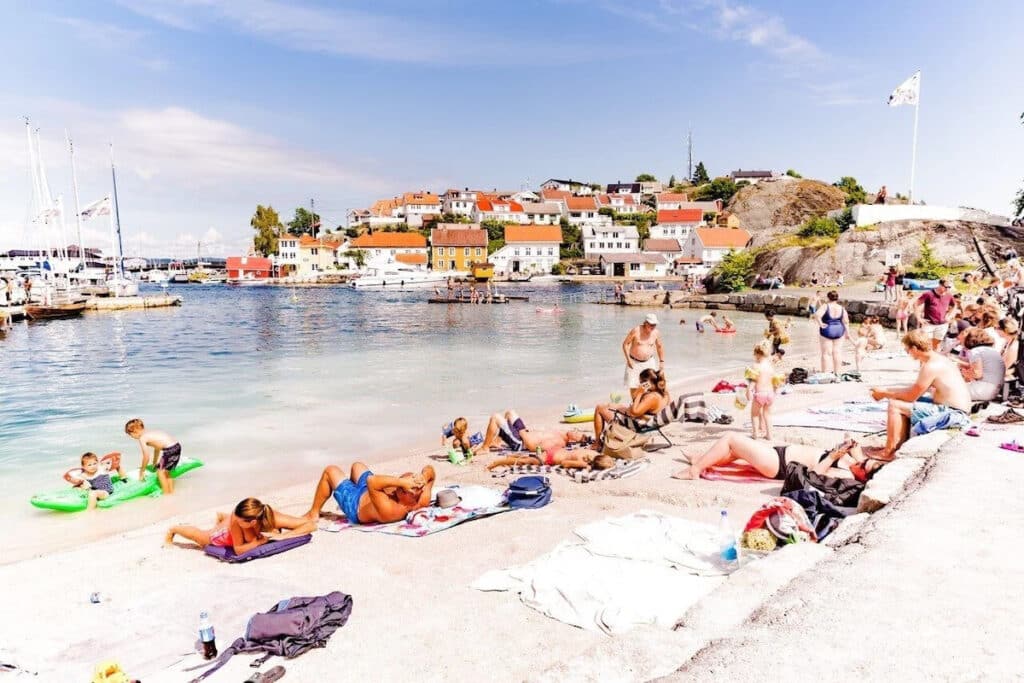 Folk som soler seg på stranden i Kragerø.