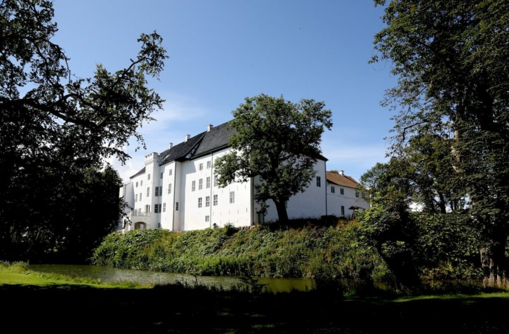Dragsholm Slot i Høvre, Danmark. Hvit bygning med grønt landskap.