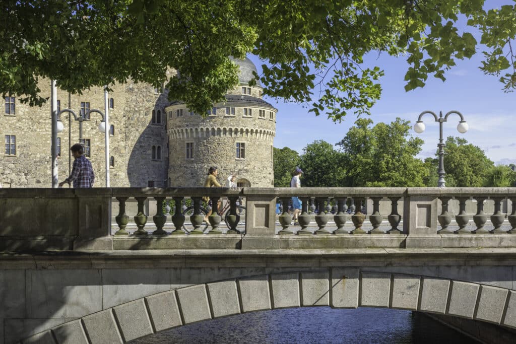 Örebro slott i bakgrunn og en bro med syklist og gående.