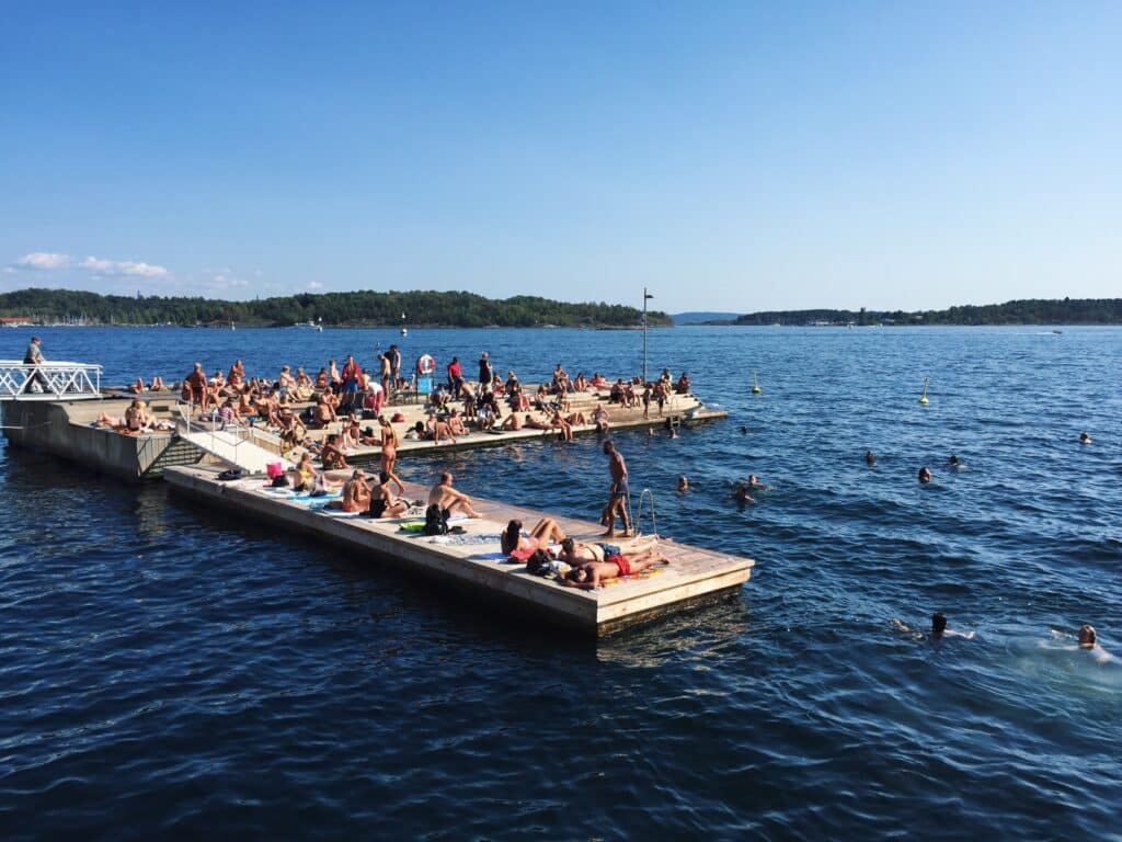 Oslo Sørenga hvor folk soler seg ved kanten og bader i vann.