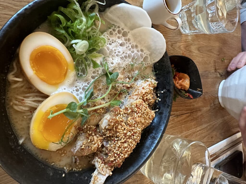 Ramen bolle med nudler, egg og sesamfrø på et bord.