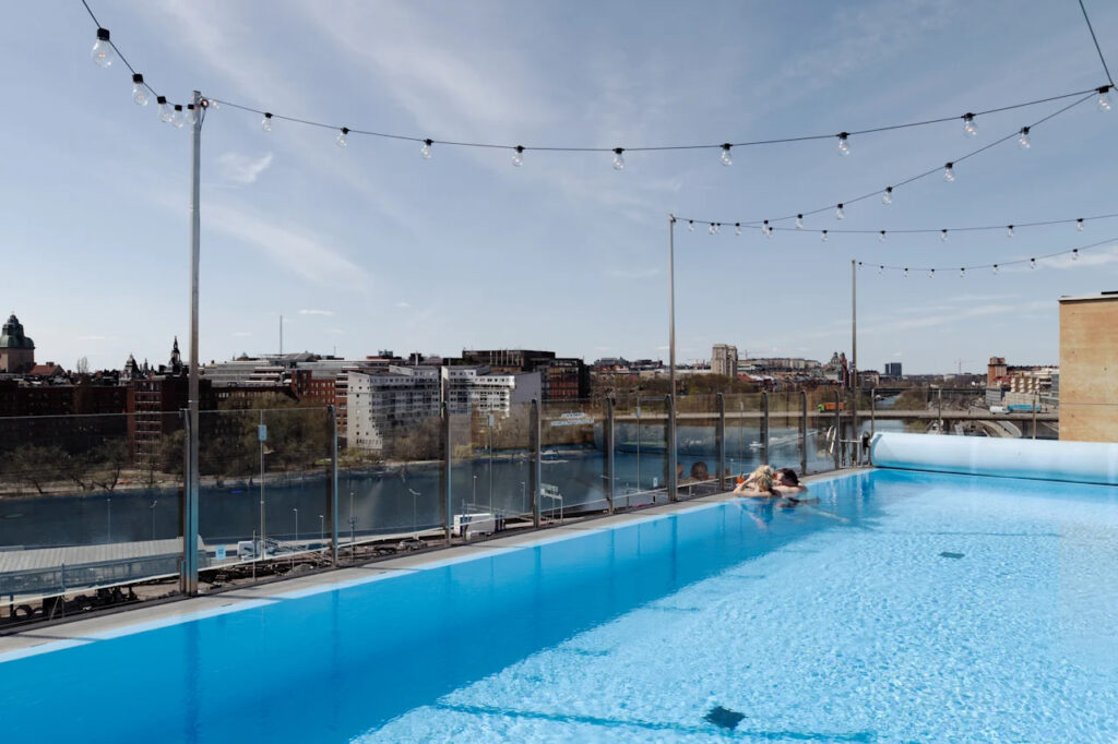 hotellbasseng på taket med par som ser ut mot utsikten over byen.