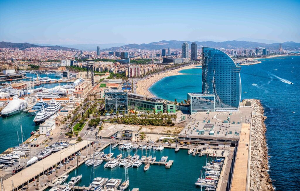 Barcelona by utsikt over stranden med havn og båt og hav. 