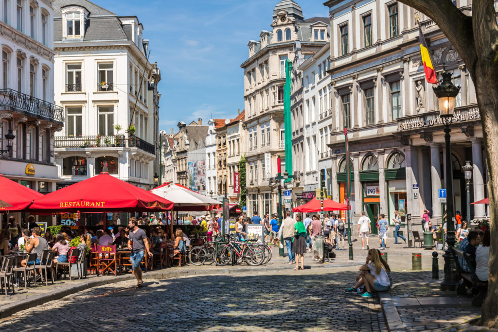 Gatene i Brussel med shopping, mennesker og blå himmel.