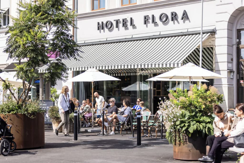 Hotell Flora utendørs med folk som sitter. 