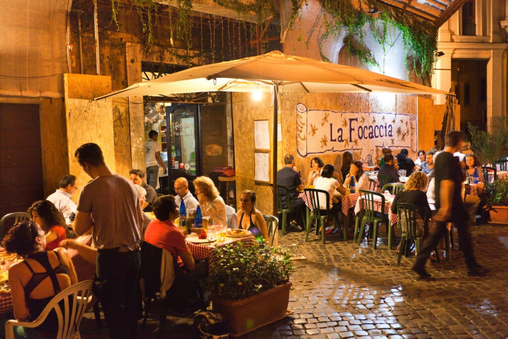 Roma by med restaurant og folkemasse som spiser. 