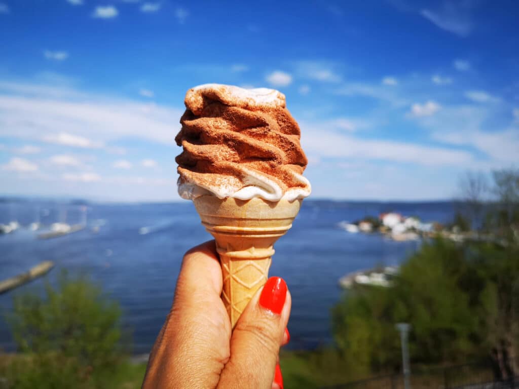 softis med sjokoladestrøssel. Røde negler, utsikt mot havn og trær.
