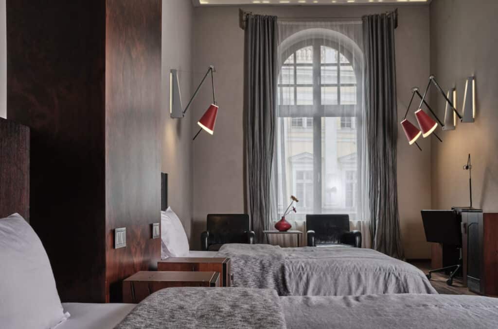 Hotellrom med to enkeltsenger og lamper på veggene.