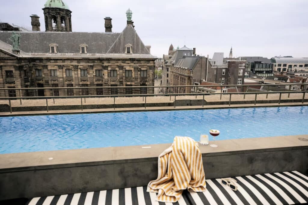 Hotell med utendørs basseng, håndkle langs kanten og bygninger.