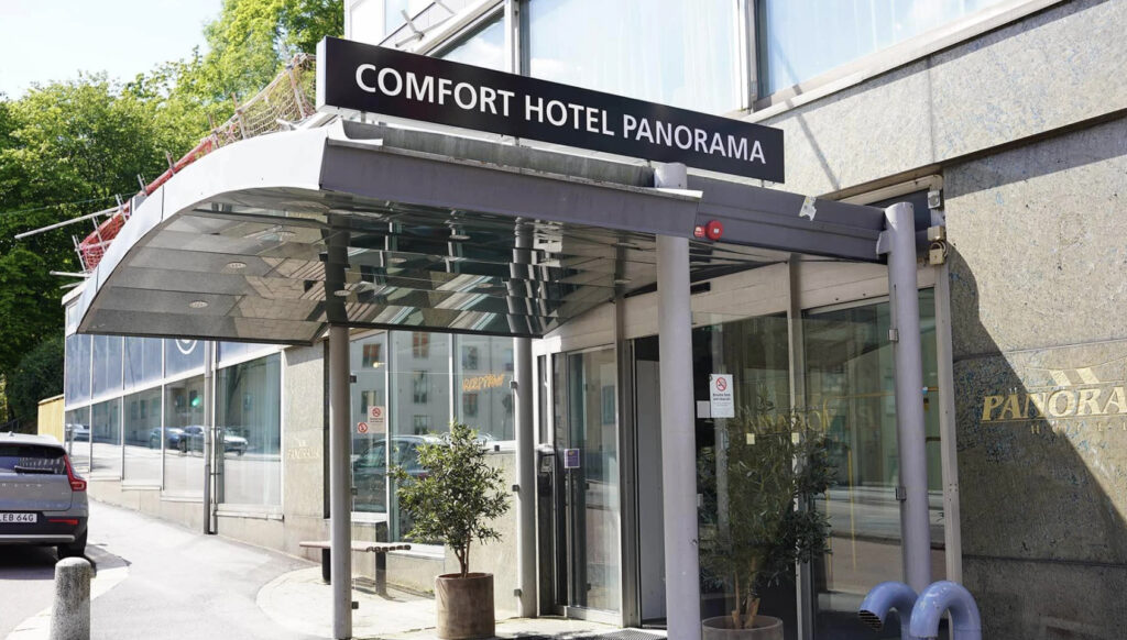 Hotellinngang og bil som står parkert utenfor.