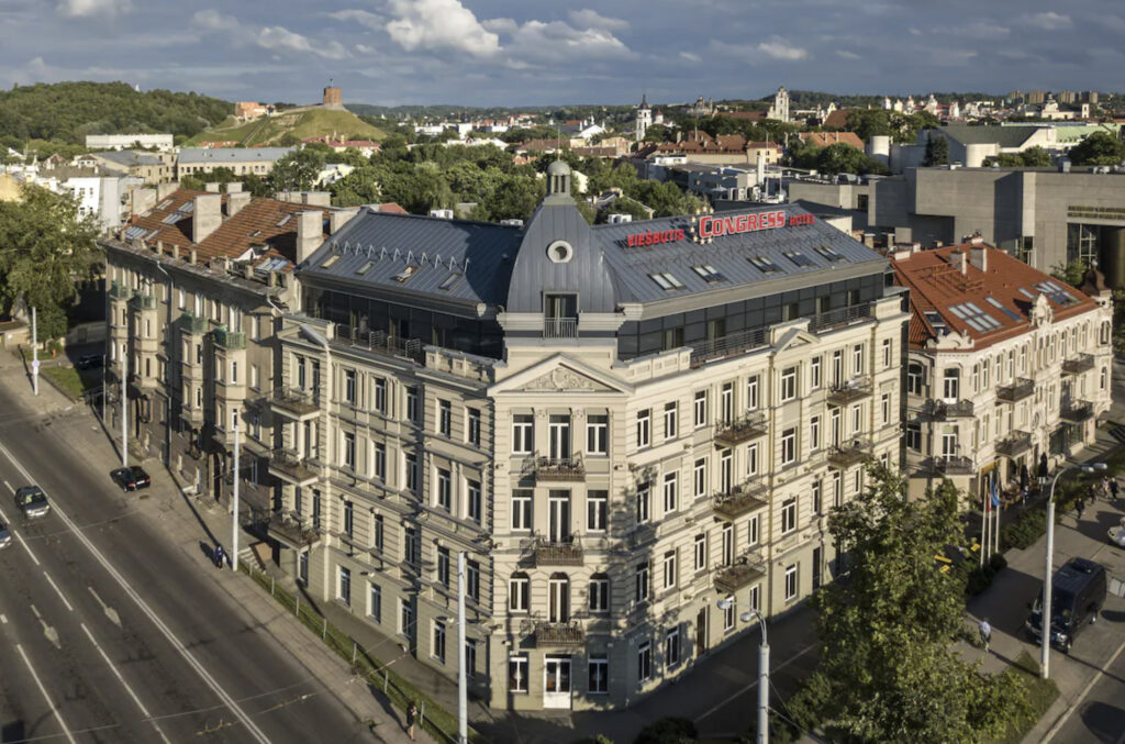 Vilnius hotellbygg rett ved bilveien og stort skilt på taket. 