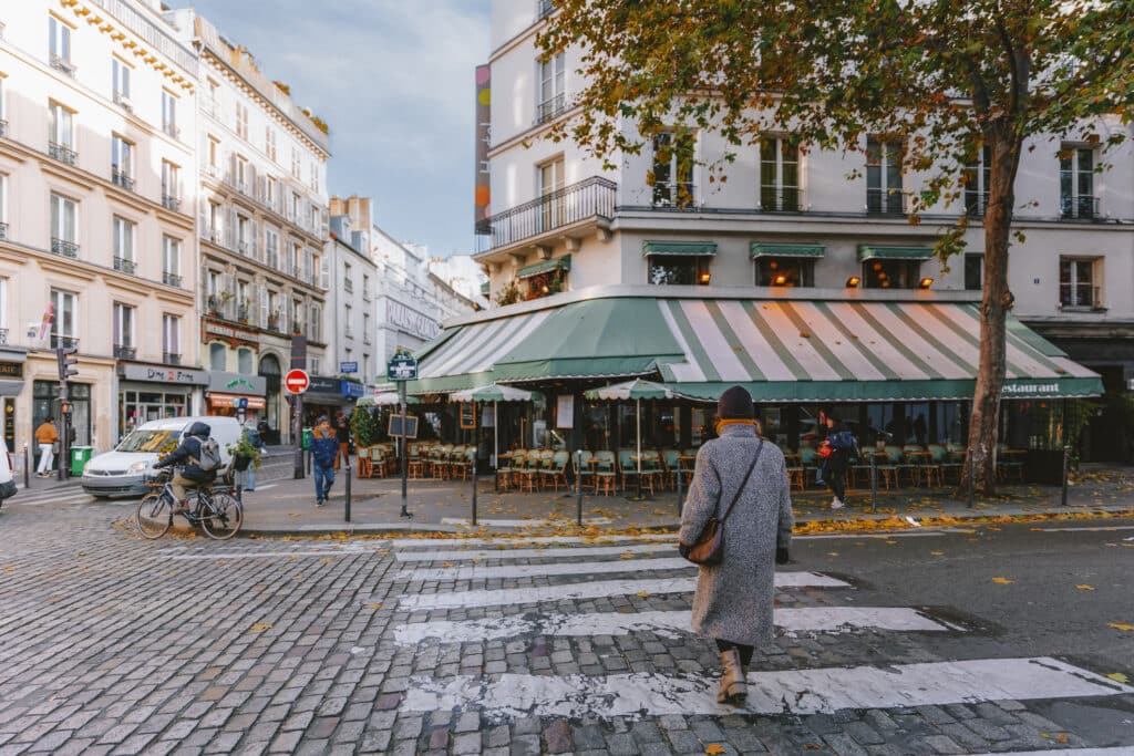 Gatene i Paris med dame i høstjakke som går over fortauet.
