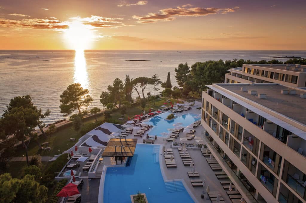 Hotell ved solnedgang, basseng og grøntområde.