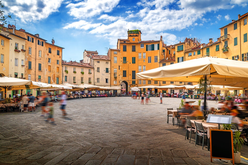 Lucca by med restauranter og folk i gatene.