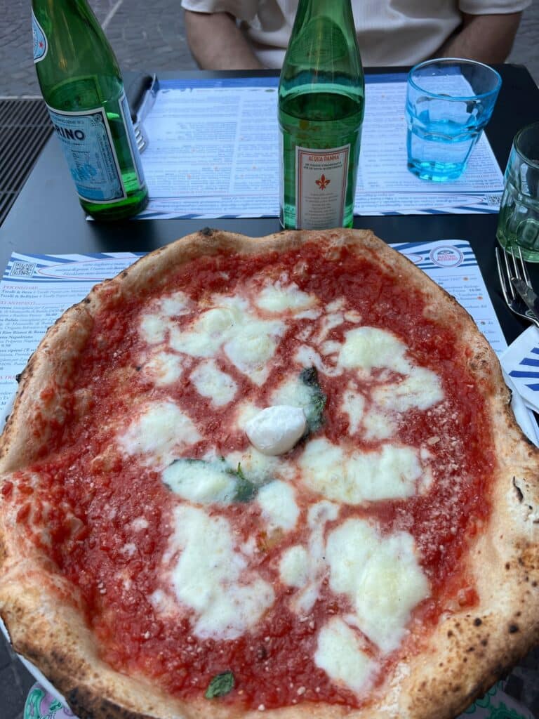 Italiensk pizza på bordet med vannflasker og glass. 